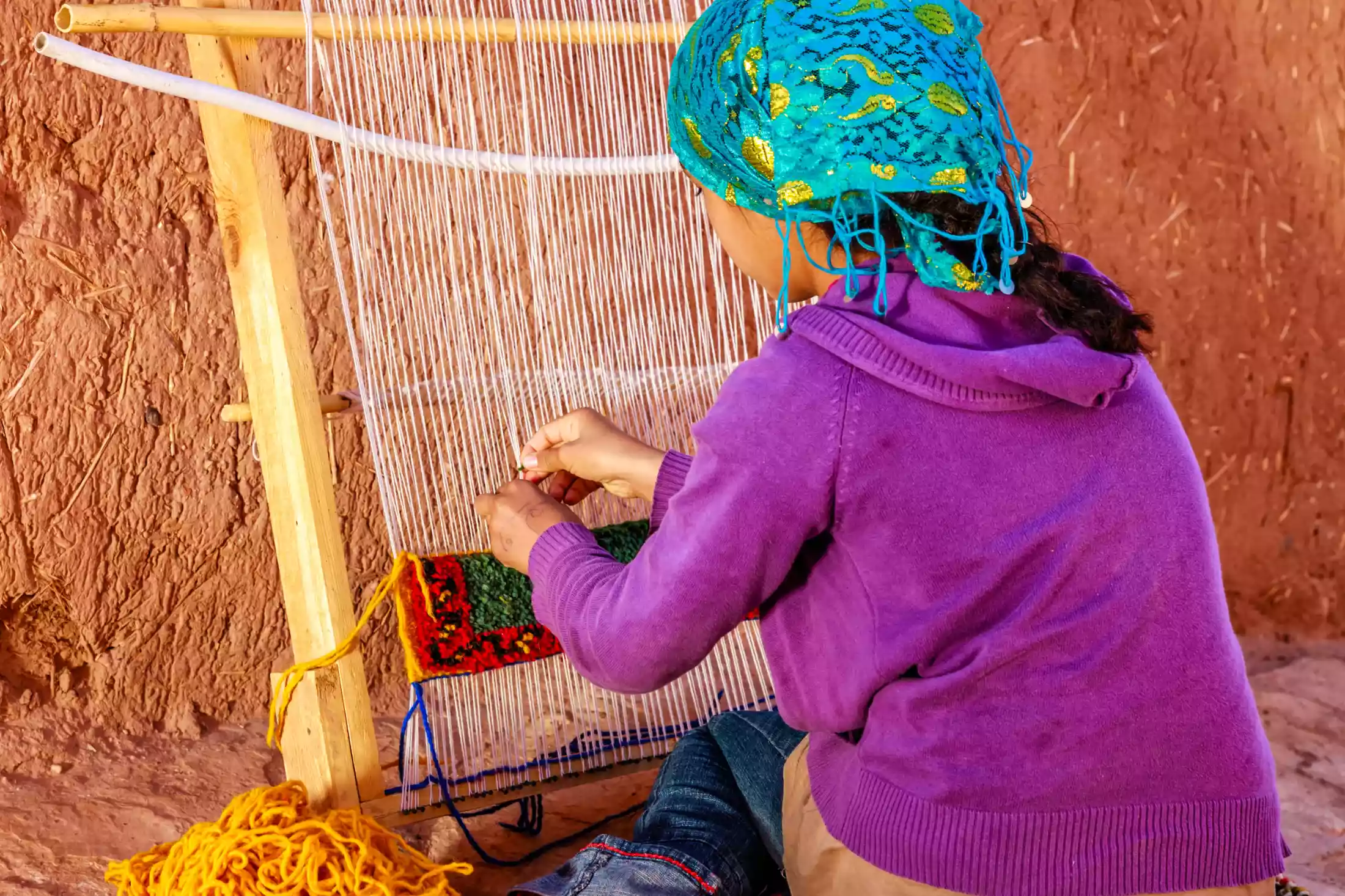 Young Berber girl weaving textiles in Morocco.